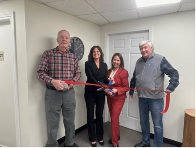 group of four people cutting a red ribbon